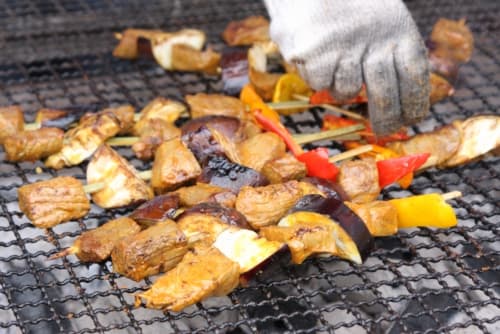 網の上で鶏肉や茄子やパプリカの串焼きをしている